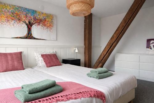 a bedroom with a large bed with green and pink pillows at Verblijf bij Bynt in Sneek