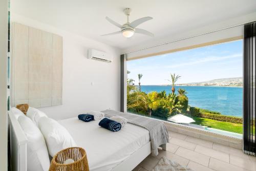 a bedroom with a view of the ocean at Beachfront Villa Mare with Jaccuzi and Infinity Pool in Kissonerga