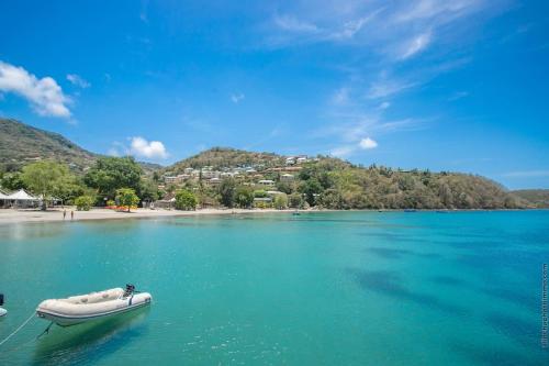 a boat in the water next to a beach at Résidence Les A'Rhum de l'Anse in Les Trois-Îlets