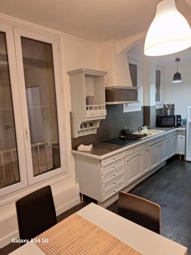 kuchnia z białymi szafkami i stołem z krzesłami w obiekcie appart hyper centre confortable w Caen