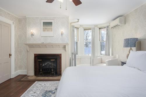 a bedroom with a white bed and a fireplace at The Berkshire Mountain Inn in Great Barrington