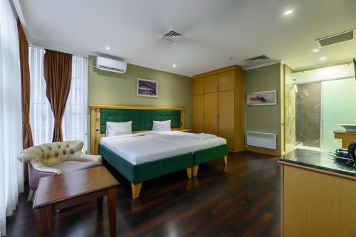 a bedroom with a bed and a chair and a table at LUVERDE HOTEL Sarkand in Almaty