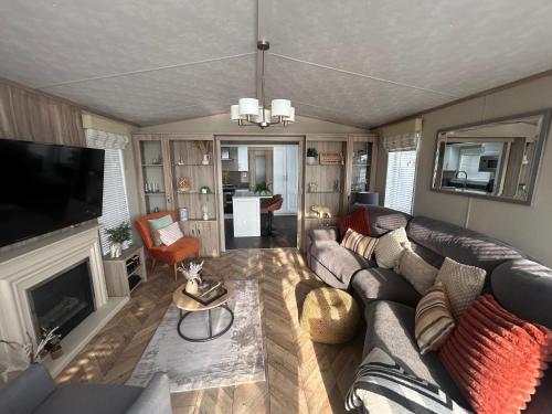 a living room with a couch and a fireplace at sunset luxury lakeside lodge with hot-tub,3 bedrooms, pet friendly in Tattershall