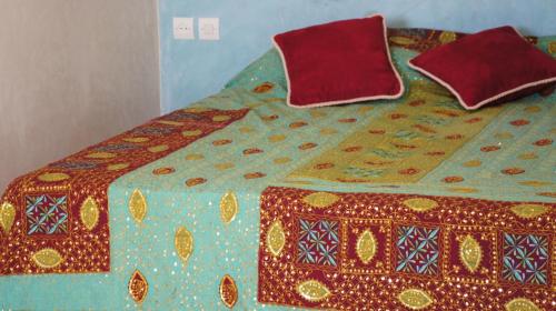 a bed with a blanket and two pillows on it at Riad Jardin des Orangers in Taroudant