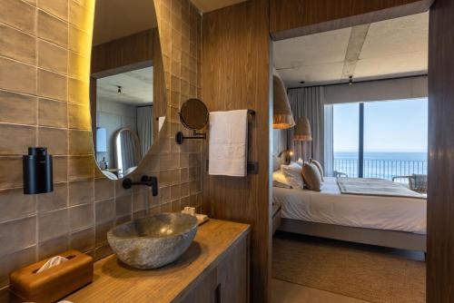 ein Badezimmer mit Waschbecken und ein Schlafzimmer mit Bett in der Unterkunft Hotel Maró in Pichilemu