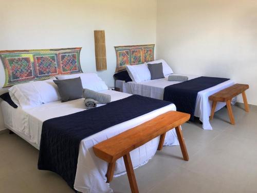 a room with two beds and a bench in it at Chalé Pitanga in Pôrto de Pedras