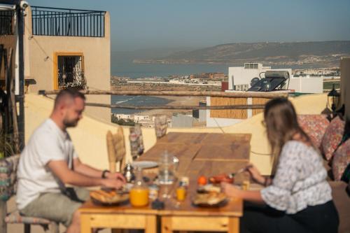 a man and woman sitting at a table with food at Eco Bay Surf Camp in Aourir