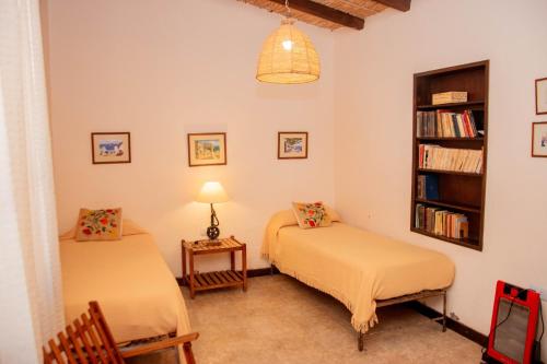 two beds in a room with a book shelf at Tilcara Casa con 3 dorm Pedacito de Cielo in Tilcara