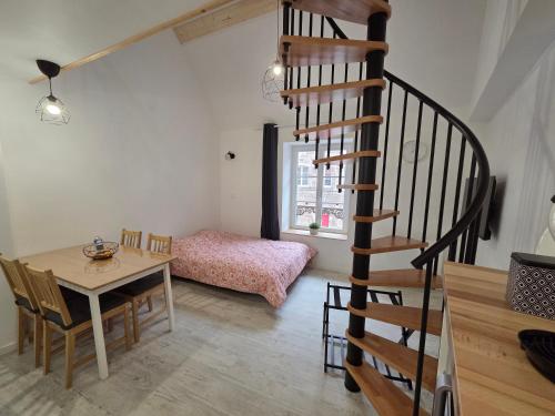 a room with a table and a spiral staircase at Nuit douce au LYS in Phalsbourg