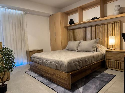 a bedroom with a large bed with a wooden headboard at Luxury apartment near Andares in Guadalajara