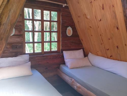 a room with two beds in a log cabin at Chalé Do Lago in Piracaia