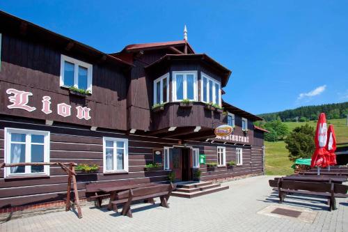 a wooden building with benches in front of it at Chata Lion in Pec pod Sněžkou