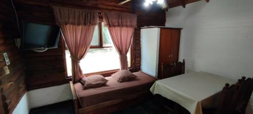 a small room with a window with a bed and a tv at Mi CASA in Sierra de los Padres