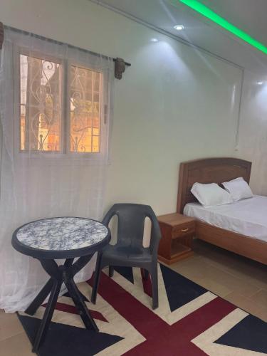 a bedroom with a bed and a table and a chair at Simple house in Lyndiane Zig in Ziguinchor