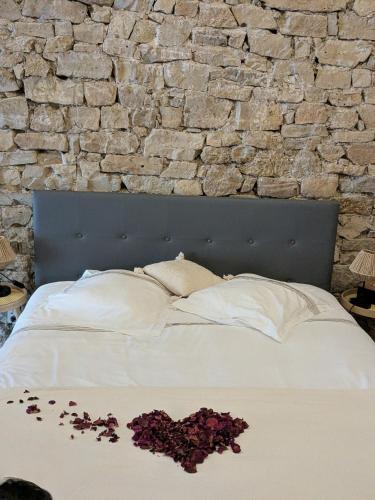 Sous la voûte في Saint-Rome-de-Tarn: سرير ذو جدار حجري وعليه أزهار
