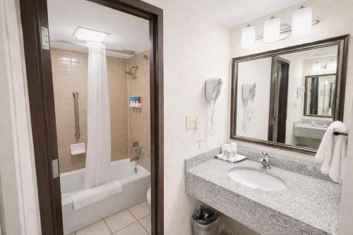 a bathroom with a sink and a tub and a mirror at Hotel Lotus Kansas City Stadium in Kansas City