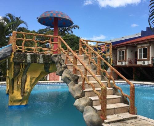 a water slide in a pool with an umbrella at Hotel La Cabaña in Ciudad Melchor de Mencos