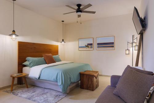 a bedroom with a bed with a ceiling fan and a couch at Hotel Hondo in Los Barriles