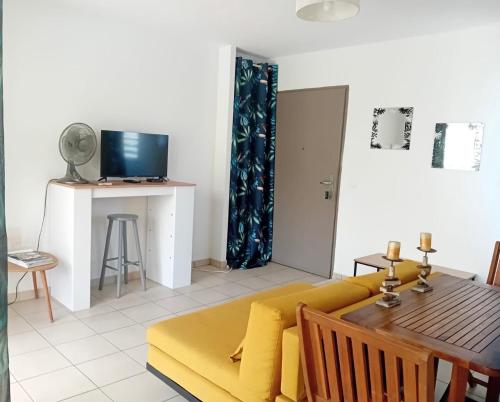 a living room with a yellow couch and a table at Des Racines & Des Ailes in Petit-Bourg