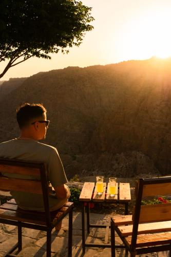 a man sitting on a bench looking at the mountains at Dana Trail Nomad Camp in Dana