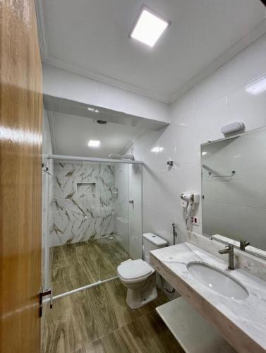 a bathroom with a toilet and a sink at Hotel Leblon in Peruíbe