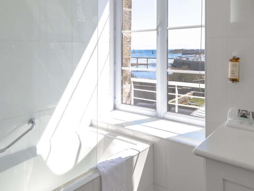 a bathroom with a window with a view of the ocean at Hotel Mercure Roscoff Bord De Mer in Roscoff