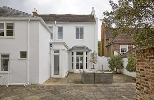a white house with a patio in front of it at Double-Bed Bedroom, Living Room and Kitchenette, private Bathroom and Utility Room available at Willow House, Shepperton in Shepperton