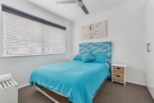 a bedroom with a blue bed and a window at H2O Holiday Apartments Unit 5 in North Haven