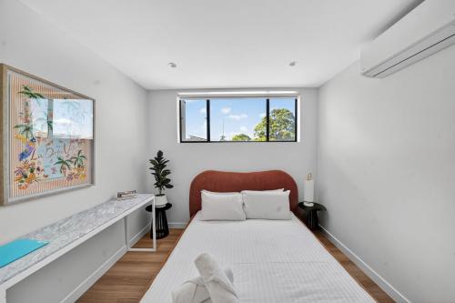 a white bedroom with a bed and a window at Bonanza Lane Hideaway in Sydney