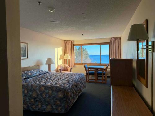 a hotel room with a bed and a table and a window at Aspen Lodge in Croftville