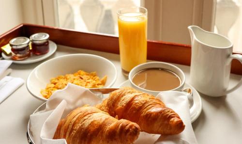 a table with a breakfast of croissants and orange juice at Ukuku Hostel & Rooftop - Quito in Quito