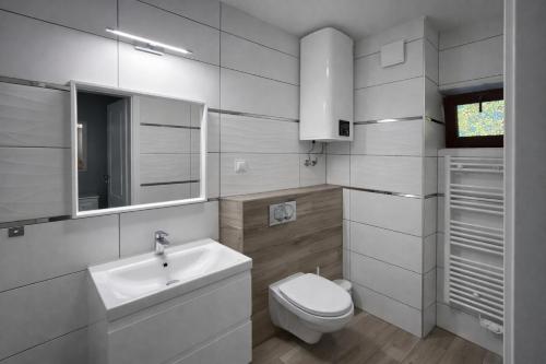 a white bathroom with a toilet and a sink at Ośrodek TVP Sarnówek in Szałkowo