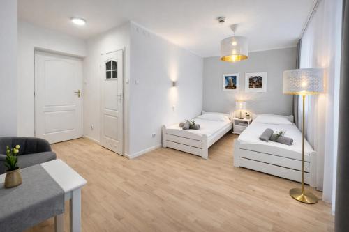a white living room with two white couches and a table at Ośrodek TVP in Ciechocinek