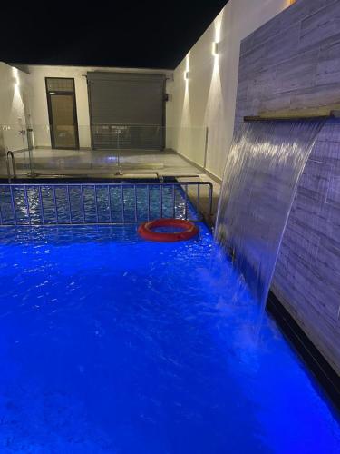 a blue pool with a waterfall in a building at اكواخ اثينا الفندقية in Jeddah