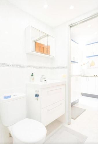 a white bathroom with a toilet and a sink at New Puerto Rico Terrace Swiming Pool in Mogán