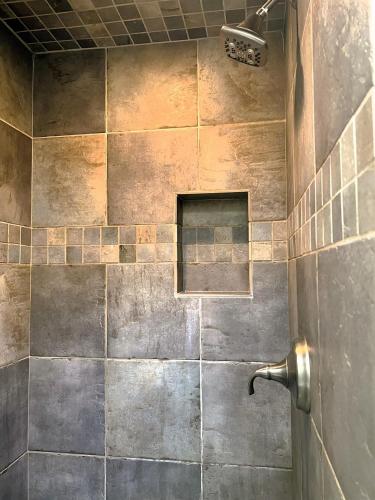 a bathroom with a shower with a tiled wall at Serenity in Santa Fe