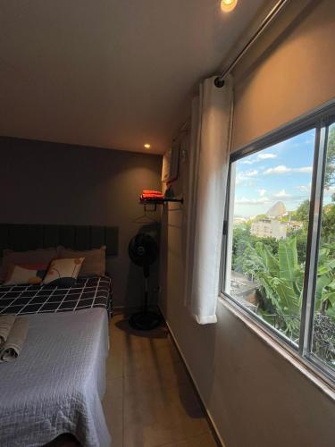 a bedroom with a bed and a large window at Excelente Espaço Econômico em Laranjeiras in Rio de Janeiro