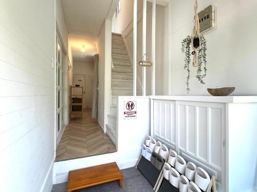 a hallway with white walls and a staircase with white chairs at Local Stay Hakodate in Hakodate