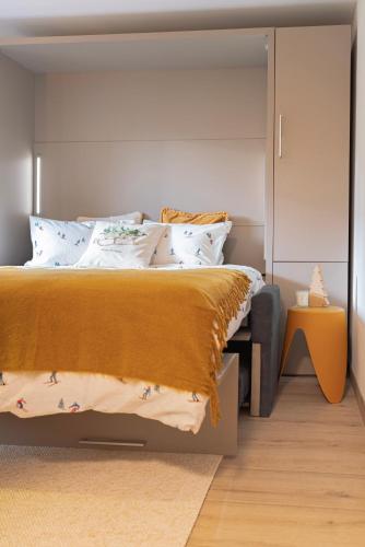 a bedroom with a large bed with a yellow blanket at Studio MORGINS avec piscine Gratuite in Morgins