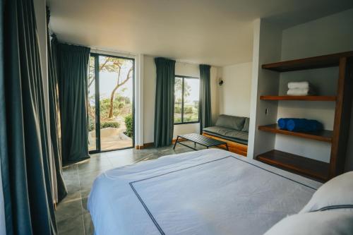 a bedroom with a bed and a couch and windows at Hotel Bohemian Lagarto in Santa Cruz