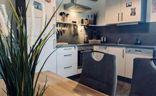 a kitchen with white cabinets and a table and chairs at Das Atelier - Kunstvoll verweilen in Ichtershausen