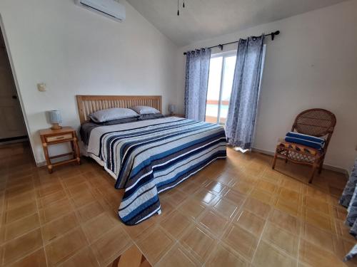 a bedroom with a bed and a chair and a window at Casa Sol-Oasis del Mar in Progreso