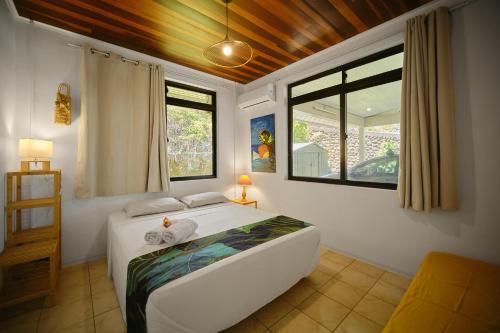 een slaapkamer met een bed en twee ramen bij Enjoy Camanukea Lodge in Mahina