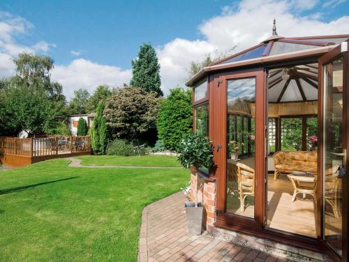 a wooden gazebo with a couch in a garden at Bridge House in Overseal
