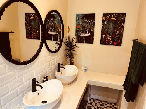 a bathroom with two sinks and two mirrors at Haze Inn Cottages Crowned in Henburg Park