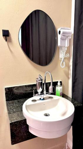 a bathroom with a white sink and a mirror at VA Apart Hotel Savassi in Divinópolis