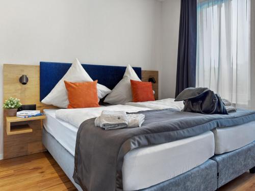 a large bed with a blue headboard and orange pillows at City Pension Heide in Heide