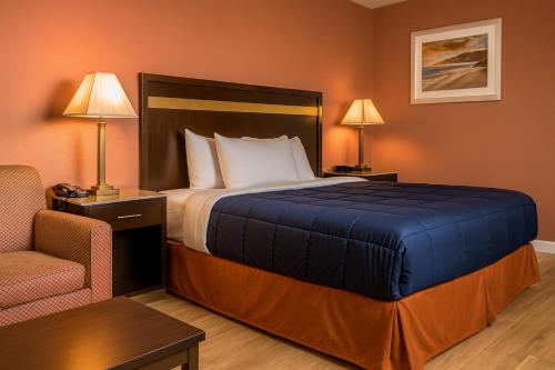 a hotel room with a bed and a chair at Elkton Lodge - Newark - Elkton University Gateway in Elkton