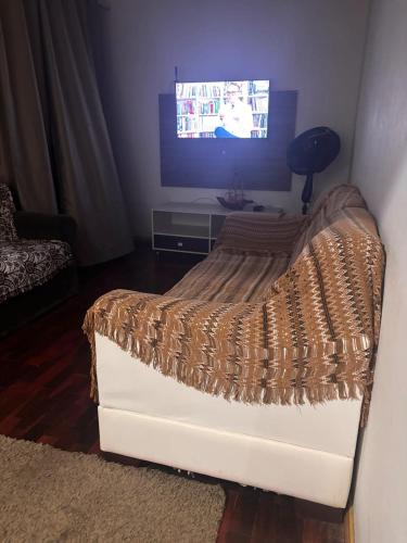 ein Bett in einem Wohnzimmer mit einem Fernseher in der Unterkunft Osório Hotel in Osório