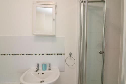 a white bathroom with a sink and a shower at Gilly's Cottage in Kingsbridge